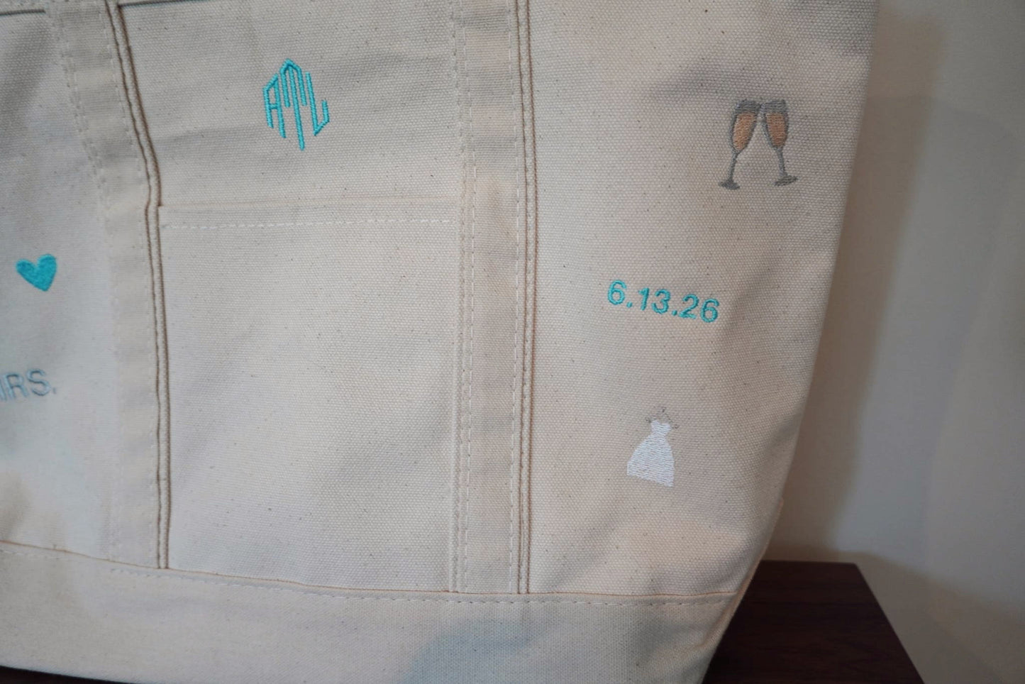 Close-up of a beige canvas tote with embroidered bridal designs and text