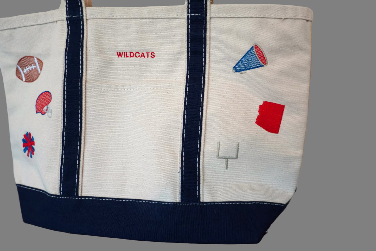 Canvas tote bag with embroidered gameday designs and 'WILDCATS' text on a wooden surface