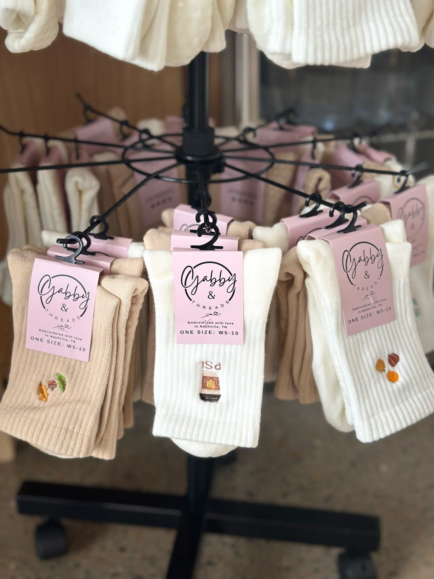 Display of socks with three socks featuring fall designs (leaves, pumpkin spice latte and pumpkins)