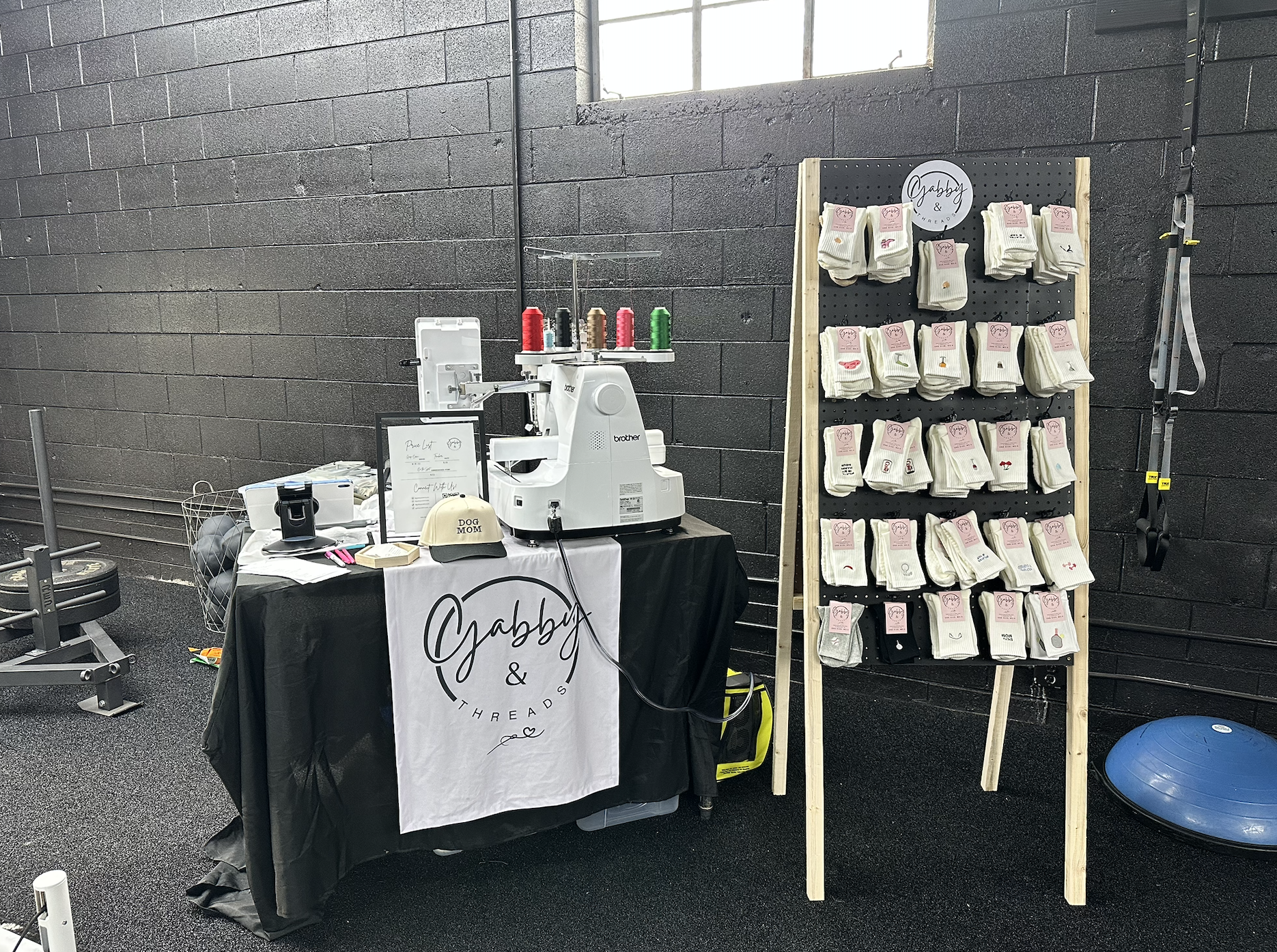 Gabby & Threads table and rack with embroidered socks in a gym setting
