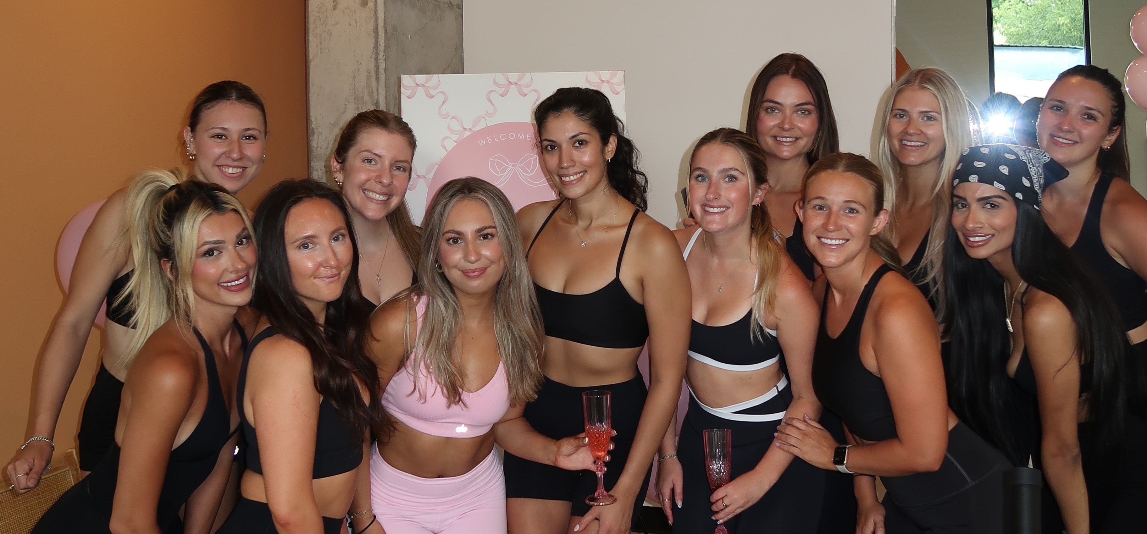 Group of women posing together in a room with a mirror reflecting their image.