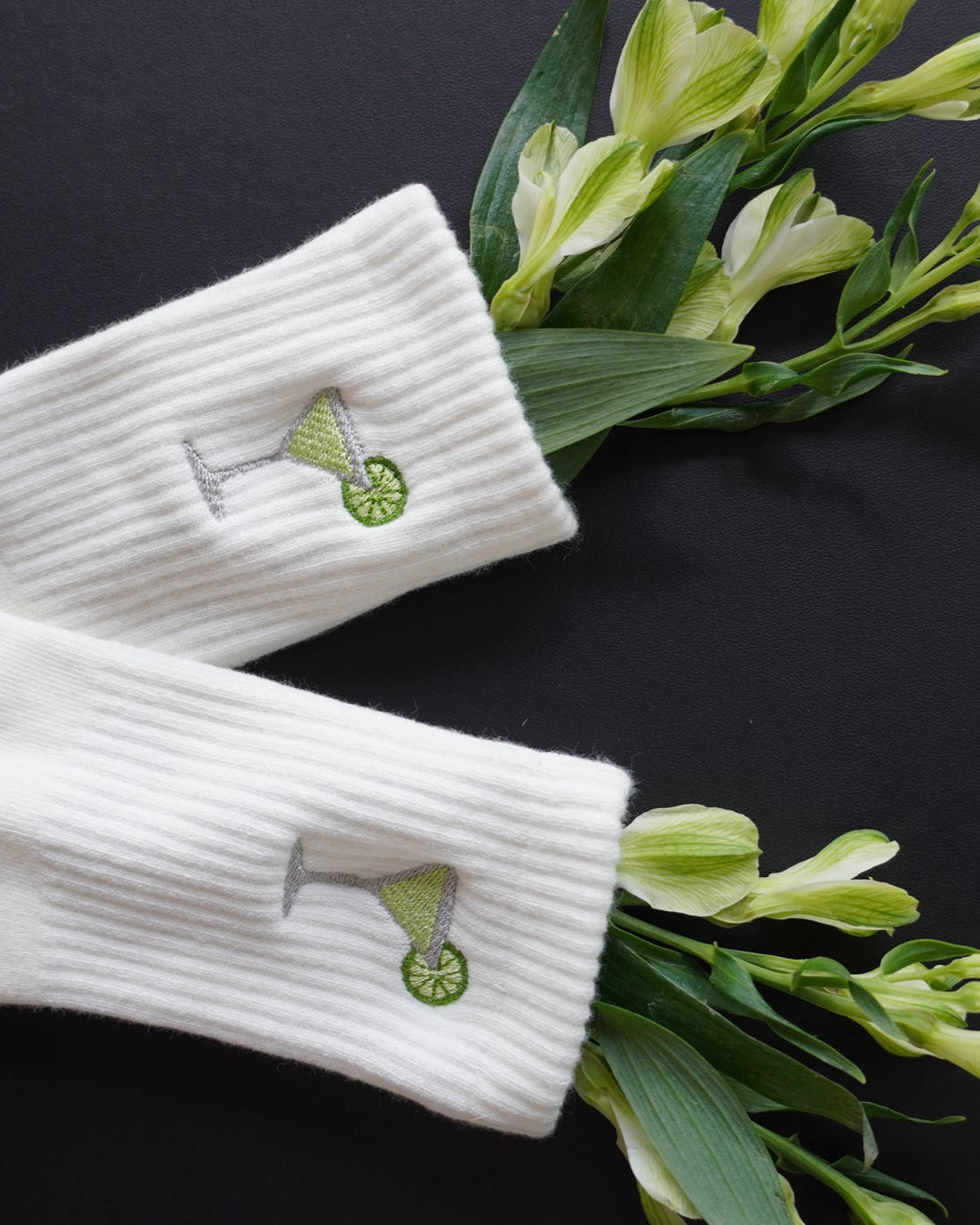 White socks with green margarita embroidery on a black background with green flowers