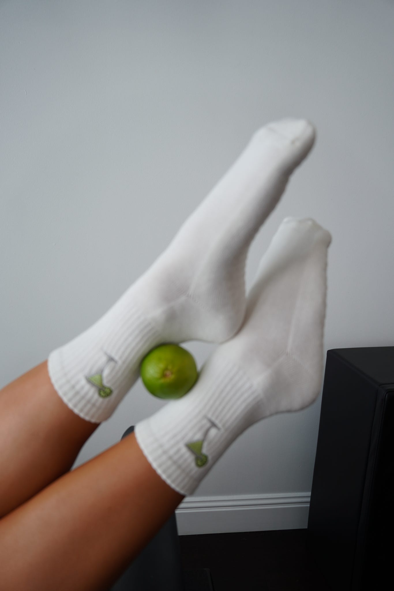 White socks with margarita with a lime held by a person against a plain background
