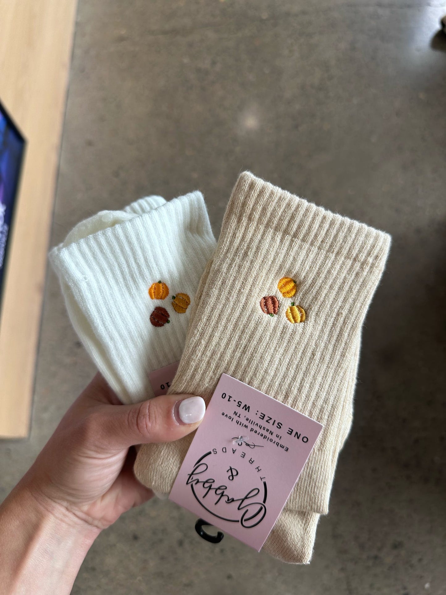 beige and white embroidered grip socks with pumpkins on them