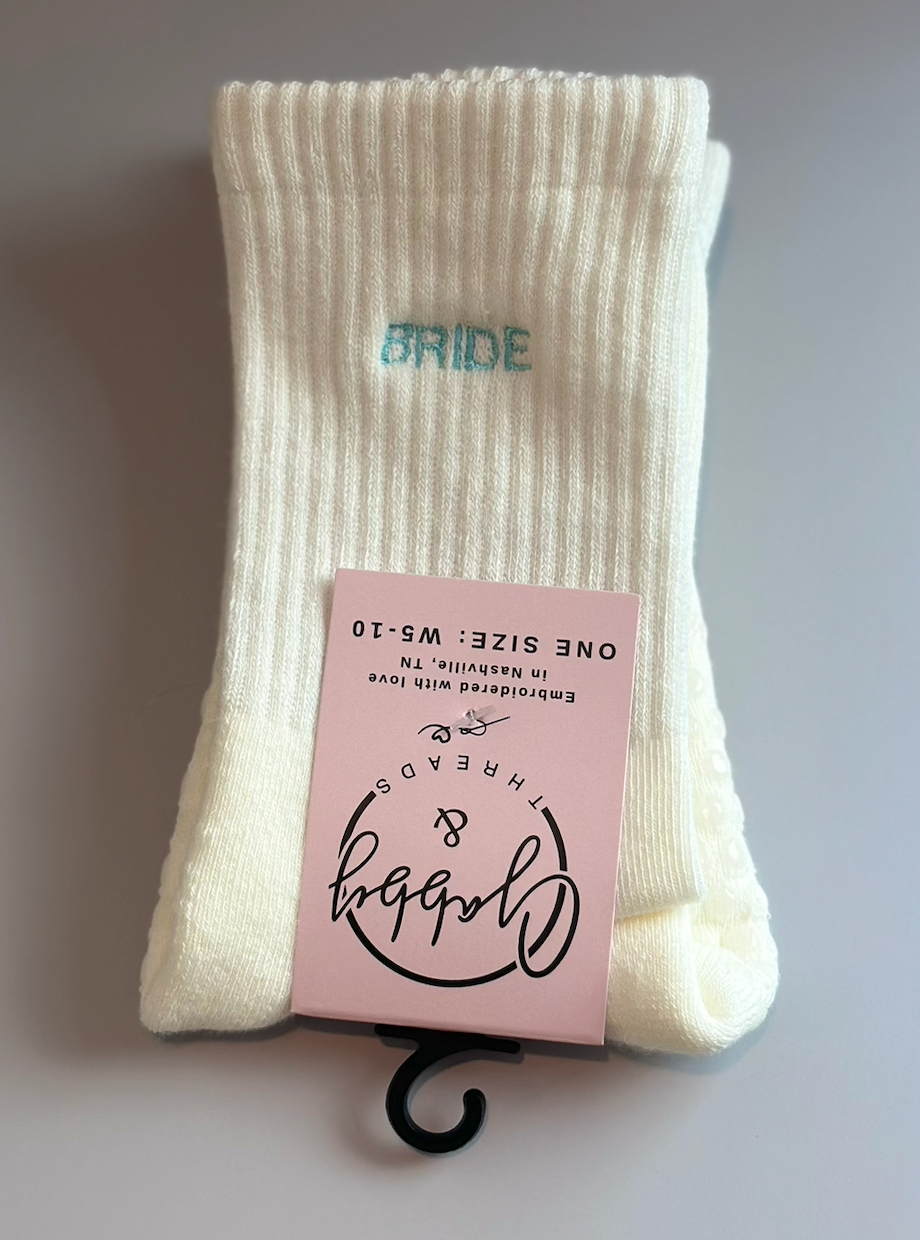 White grip socks with 'Bride' text against a gray background