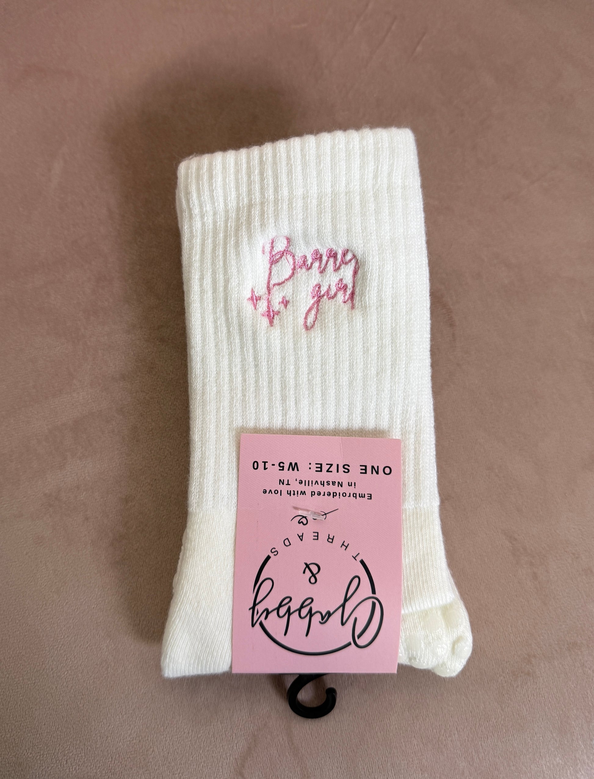 a pair of white grip socks with the words "Barre girl" embroidered on them 
