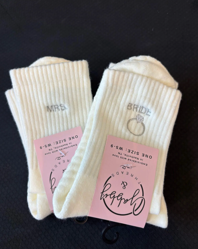White socks with 'bride' and ring design with another pair of white socks that say "Mrs." on them