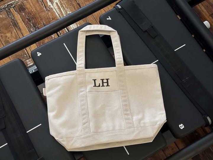 canvas tote bag with 'LH' monogram on a Lagree megaformer