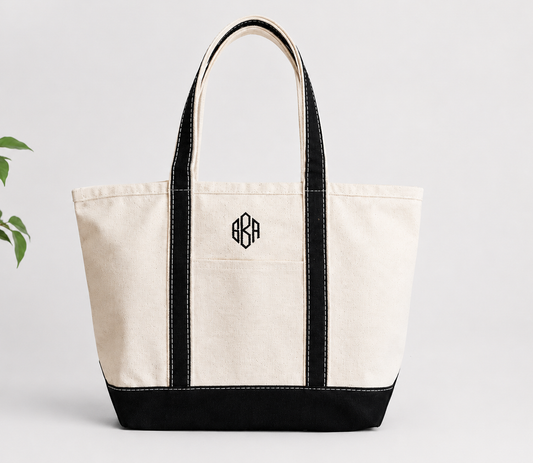 canvas tote bag with black accents and a monogram on a light gray background