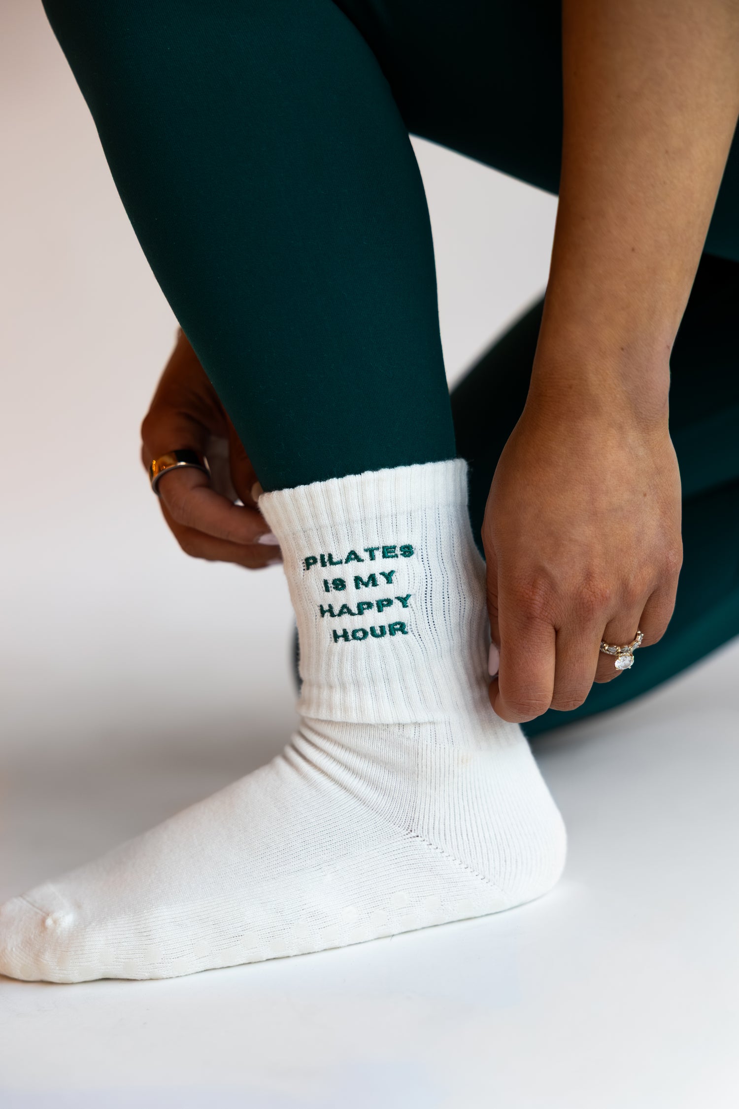 a person is wearing a pair of white grip socks that say "pilates is my happy hour"