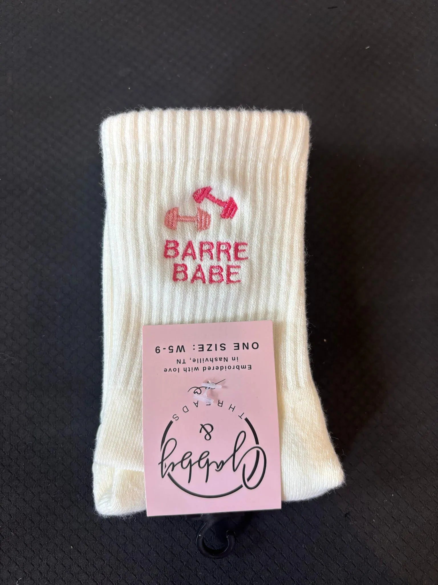 White grip socks with 'Barre Babe' embroidered on them on a black background