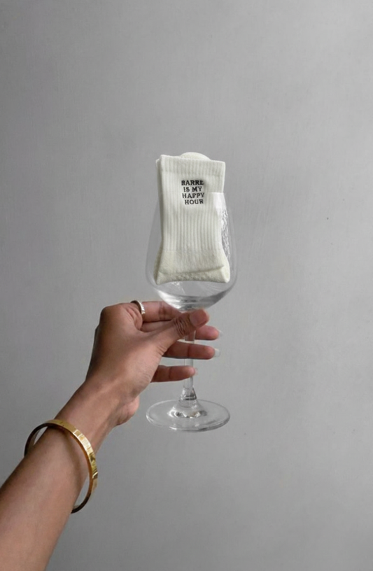 Hand holding a wine glass with a white sock inside against a gray background