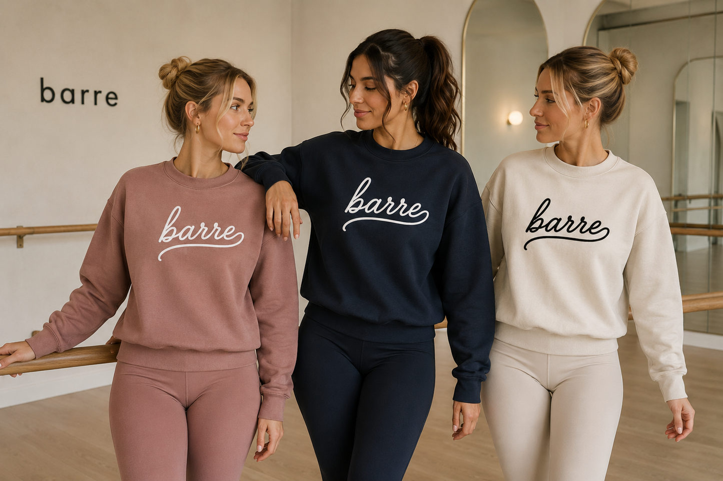 Three women wearing 'barre' sweatshirts in a barre studio.