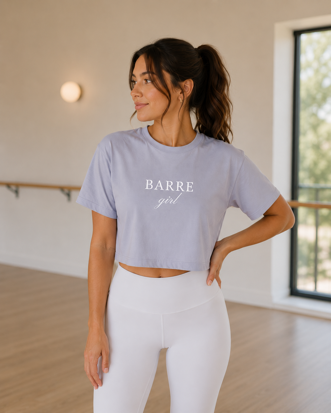 A women is in a barre studio wearing a cropped t-shirt that has the words “barre girl” embroidered on them
