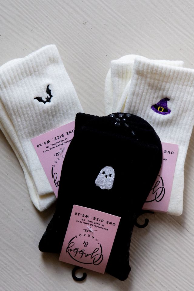three pairs of halloween grip socks featuring different embroidered icons. The three icons are a bat, a ghost and a witch hat