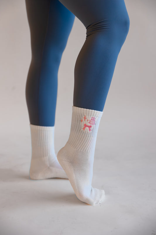 White socks with a small birthday design with blue leggings on a plain background