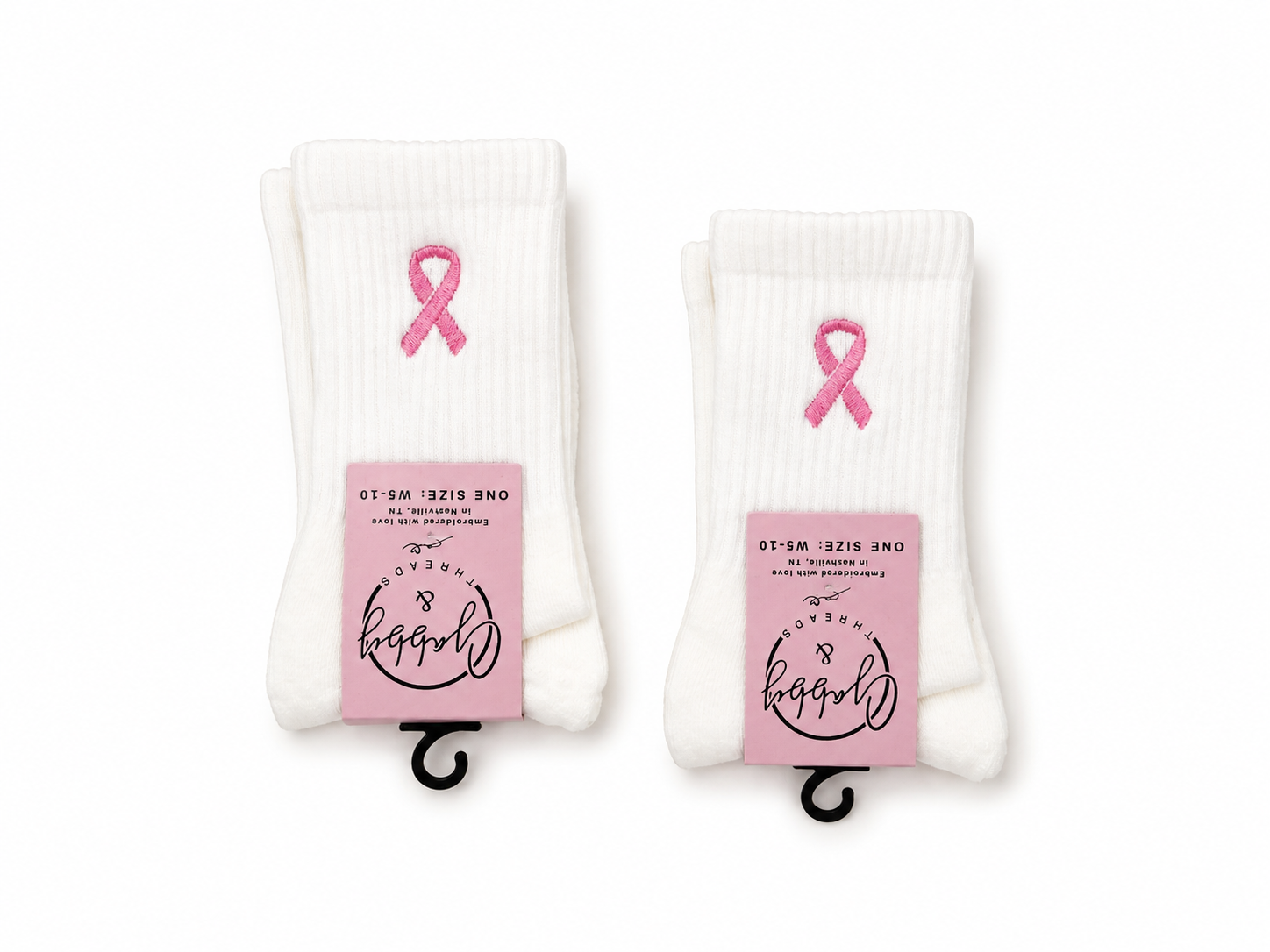 two pairs of white grip socks with embroidered breast cancer ribbons on them