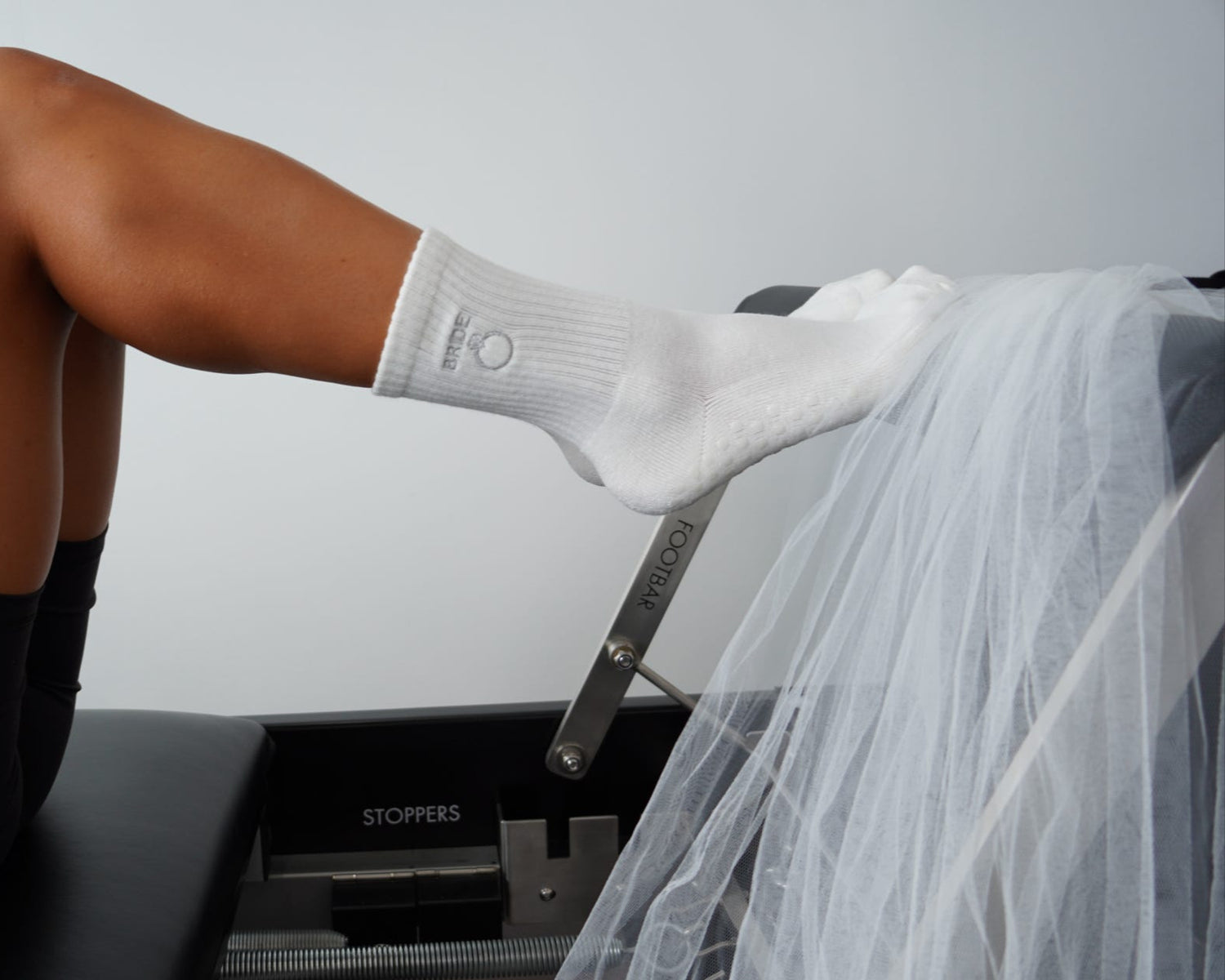 Person wearing white grip socks with "BRIDE" and ring design on a reformer 