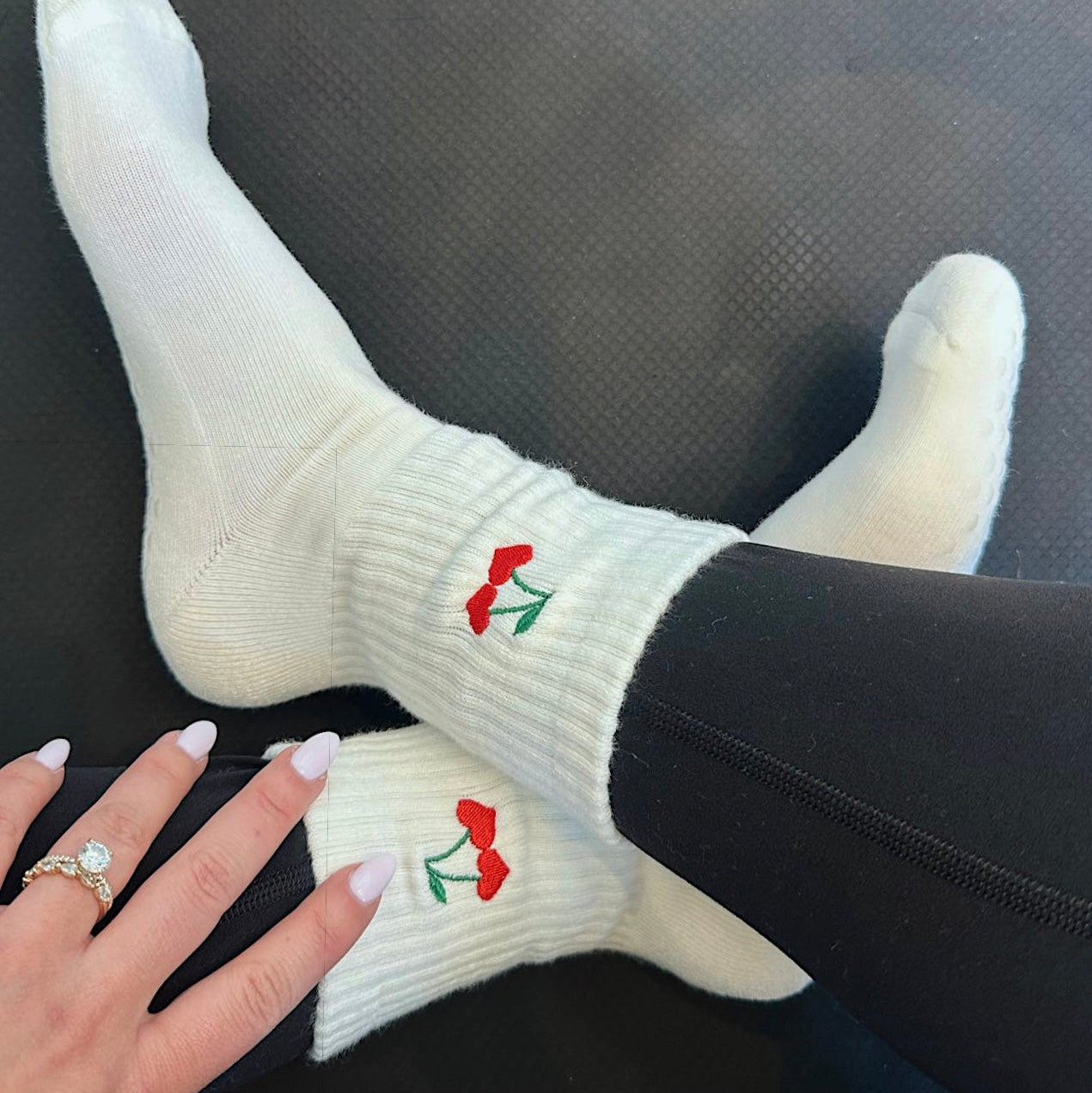 White socks with cherry hearts worn by a person on a dark surface