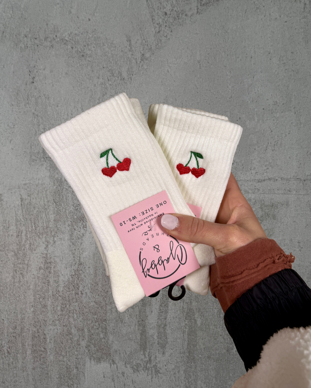two pairs of white grip socks with cherry hearts embroidered on them