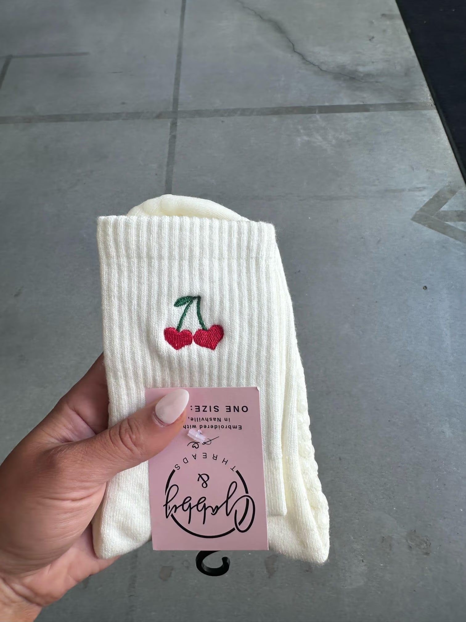 a pair of white grip socks with cherry hearts embroidered on them