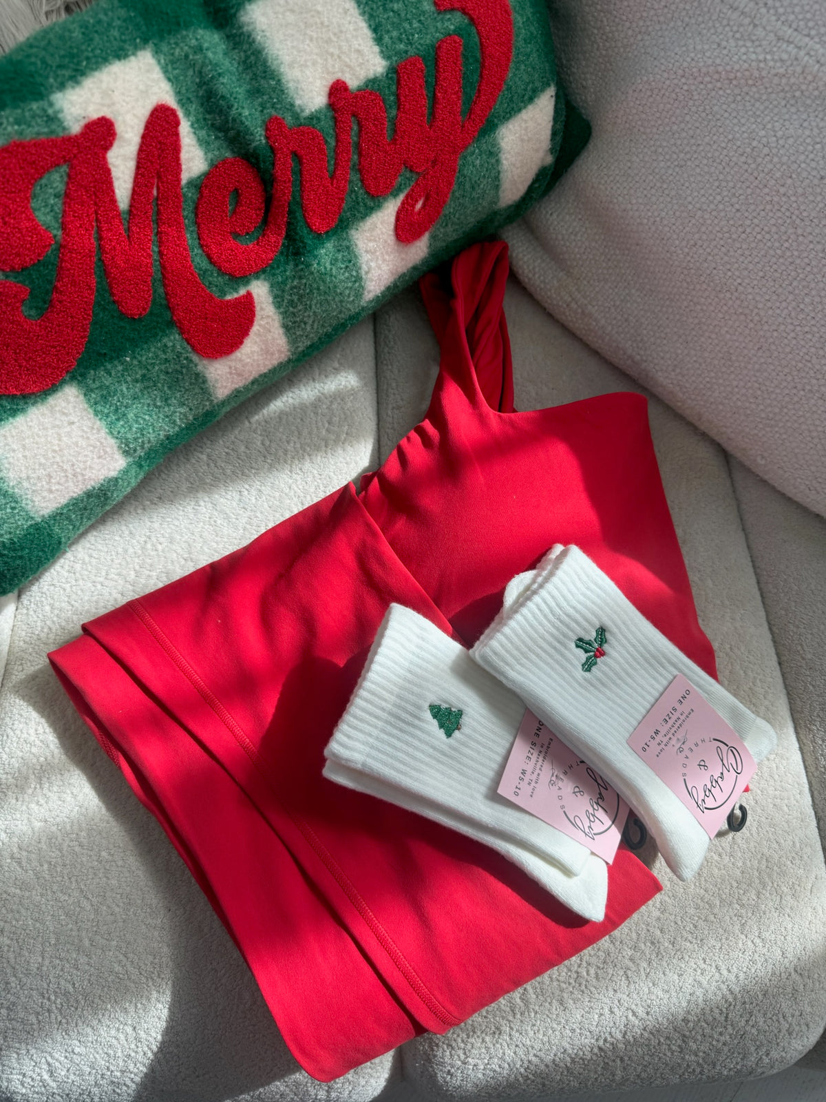 two pairs of socks featuring two different christmas icons (a christmas tree and a holly spring)