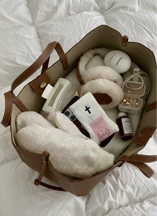 a pair of white grip socks with an embroidered cross sits inside a purse