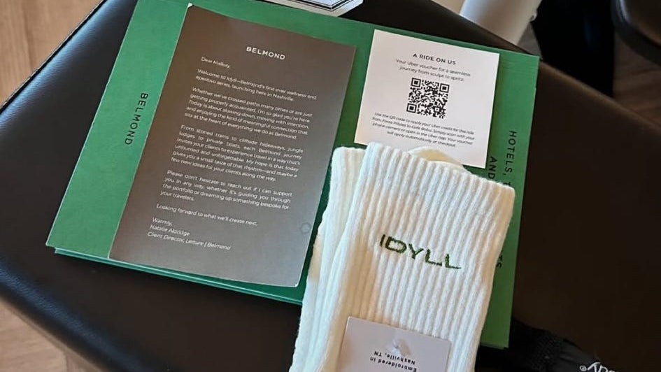 Pair of white socks with 'Idyll' branding on a green card with text and a QR code.
