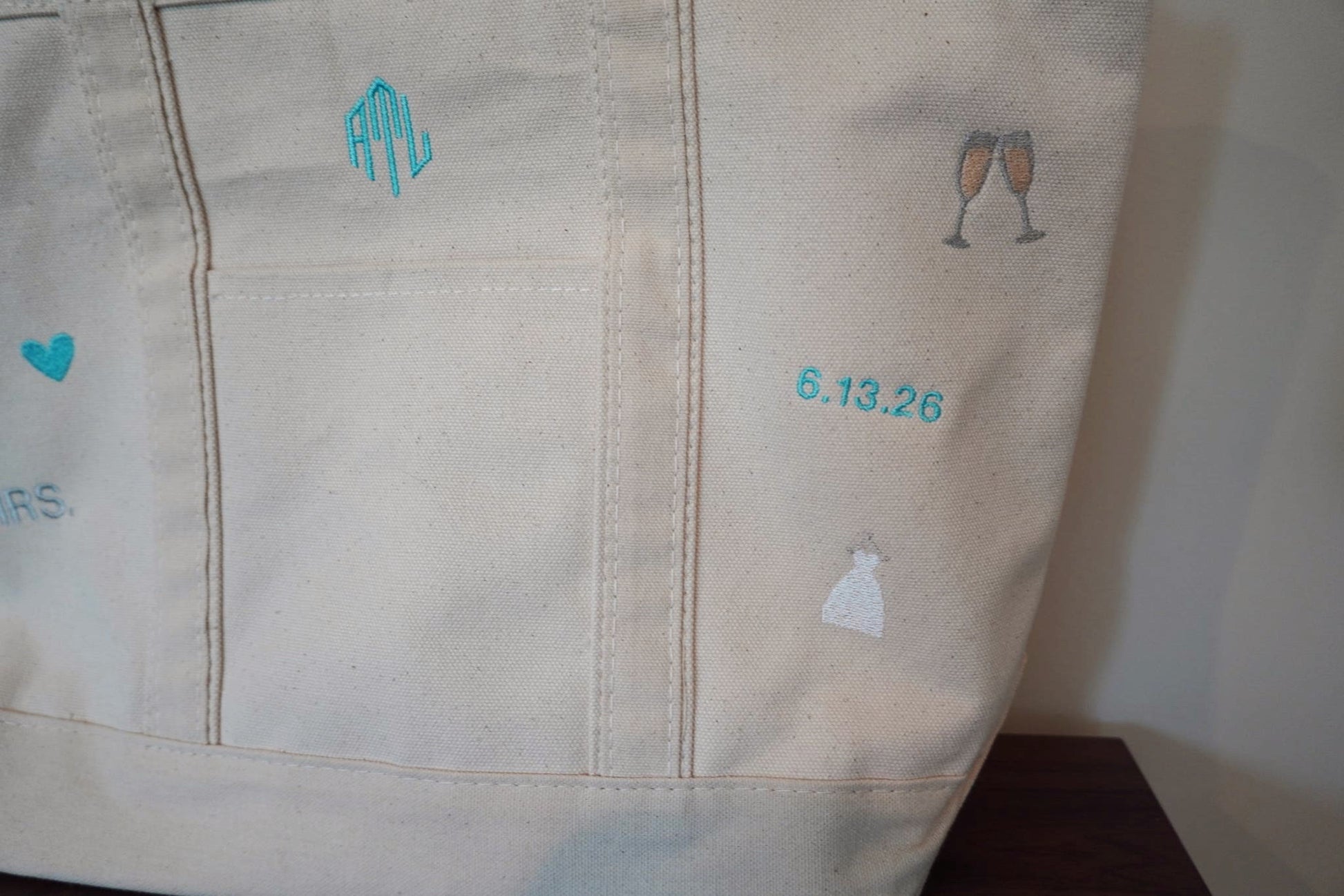Close-up of a beige canvas tote with embroidered bridal designs and text