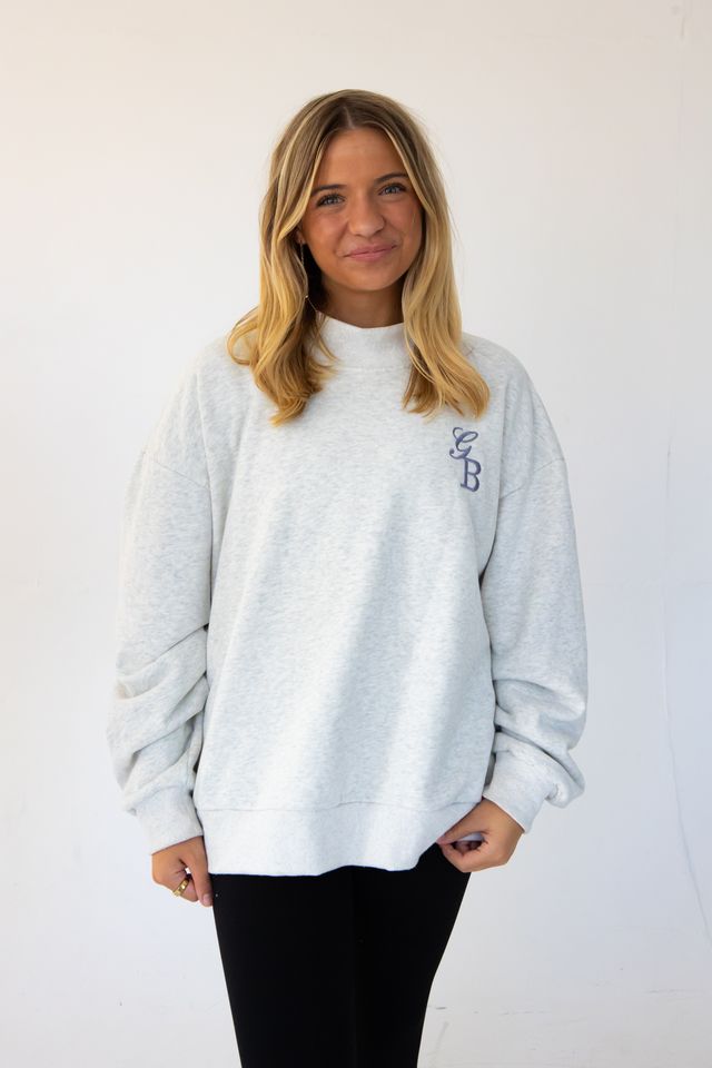 a model is wearing a custom embroidered mock neck sweatshirt with her initials 