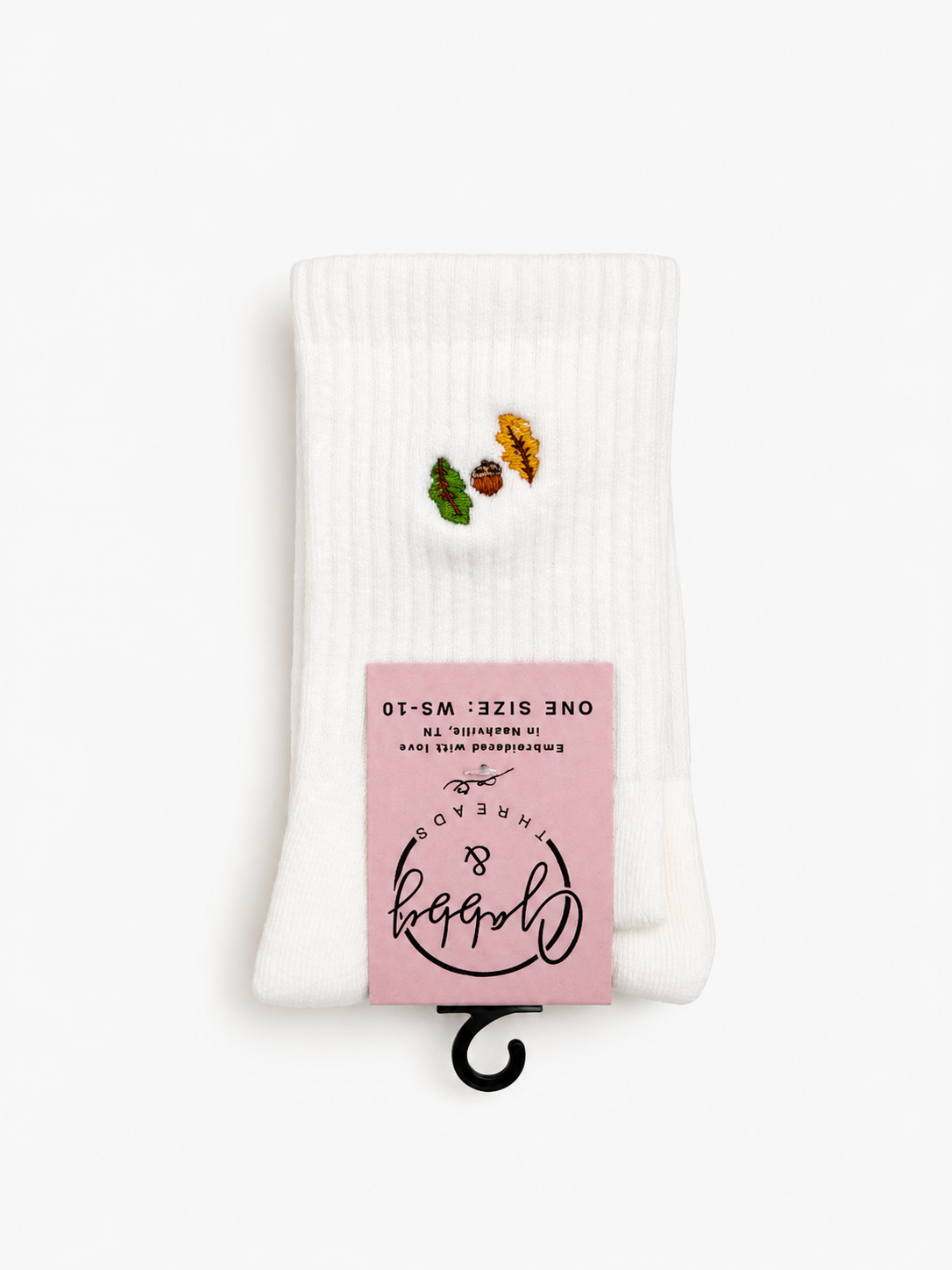 a pair of white socks with two fall inspired leaves and an acorn embroidered on them