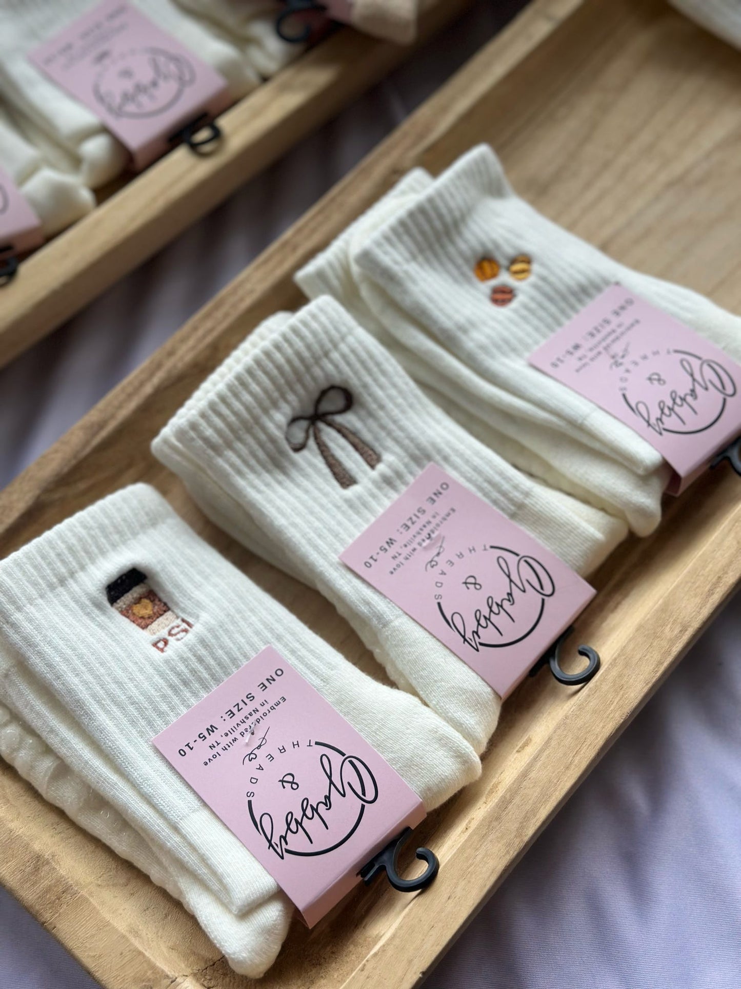 Display of socks with three socks featuring fall designs (brown coquette bow, pumpkin spice latte and pumpkins)