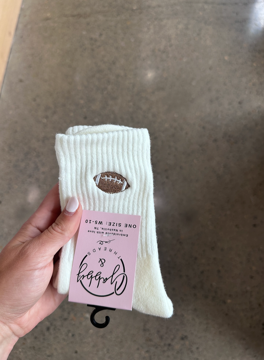 White socks with a football design held by a hand against a gray background