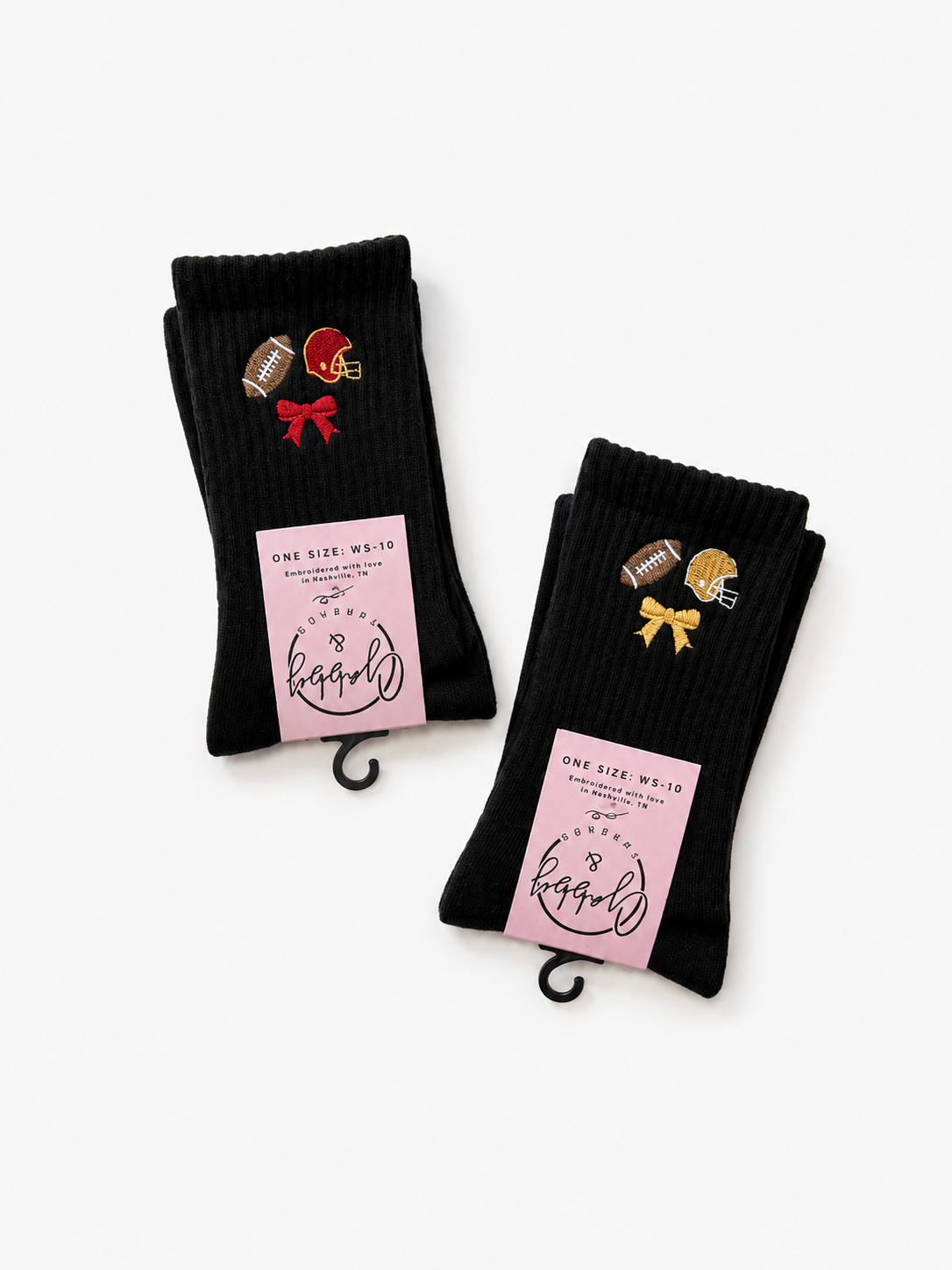 Two pairs of black ribbed crew socks with football-themed embroidered details and pink paper tags, displayed on a clean white background.