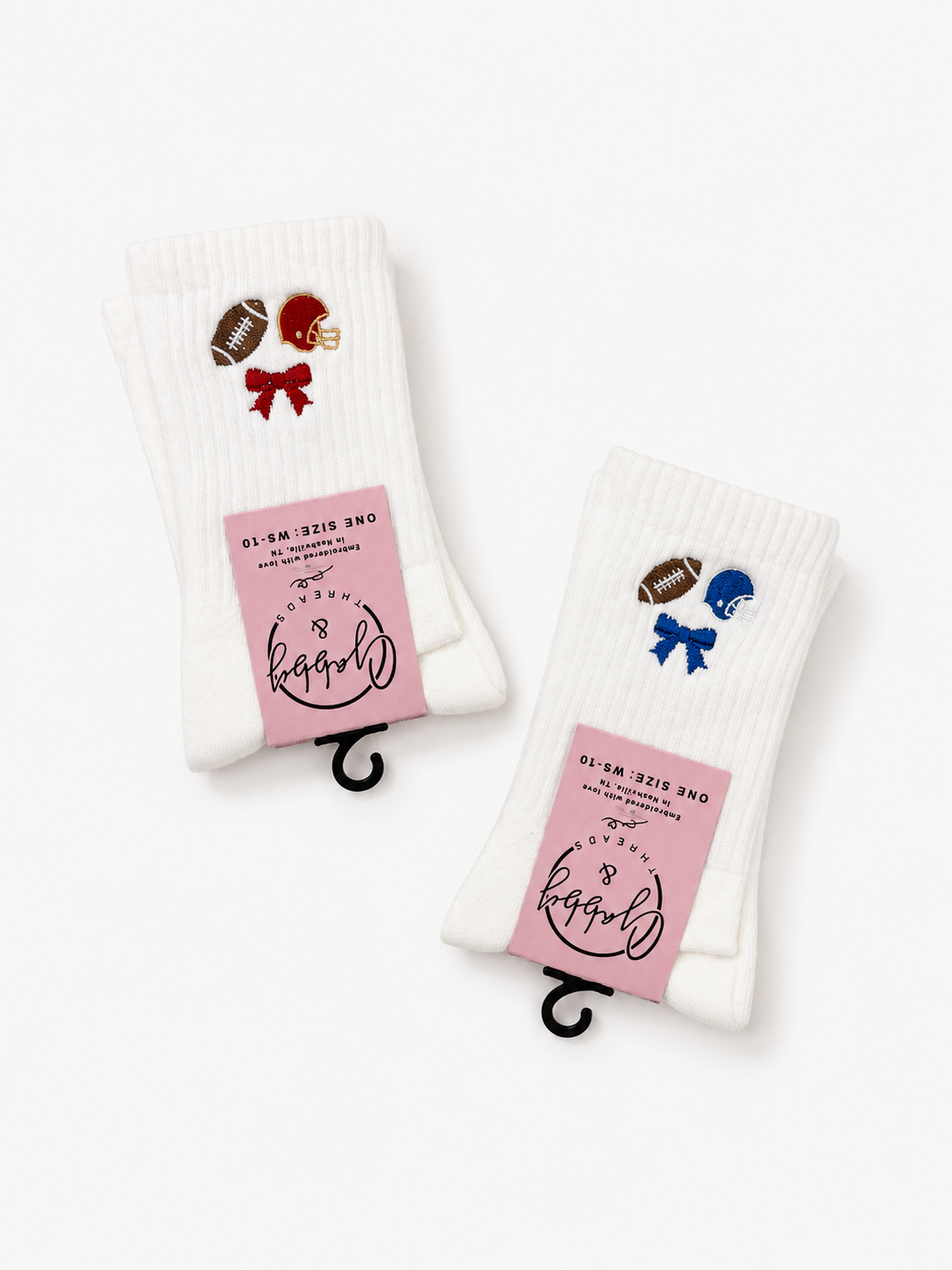 Two pairs of white ribbed crew socks with small football-themed patches and pink paper bands, displayed on a clean white background.