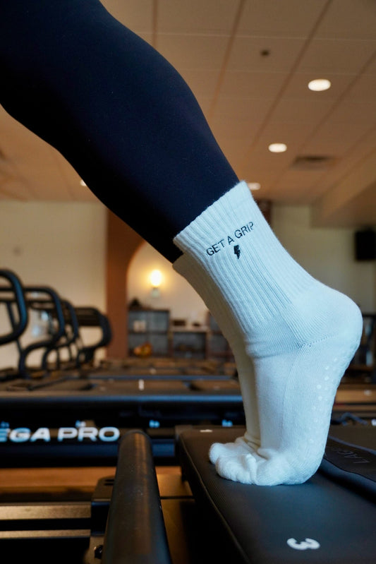 a person is wearing a pair of white grip socks with the words "get a grip" on them on a pilates reformer