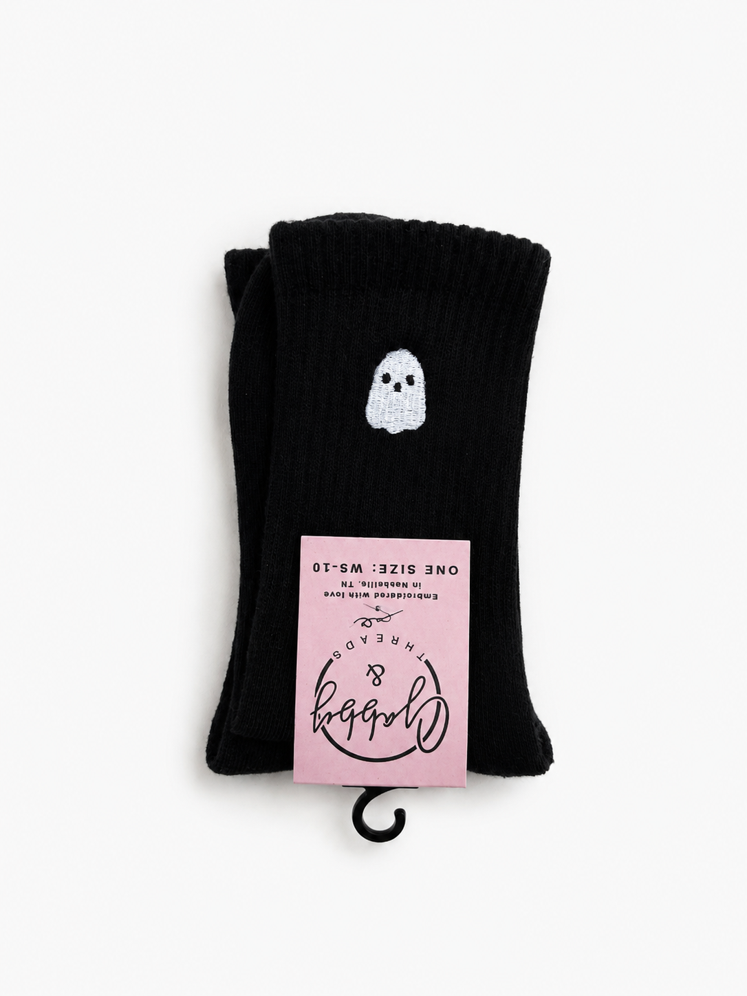 A pair of black crew socks folded together, featuring a small white ghost graphic embroidered on it and a pink hangtag 