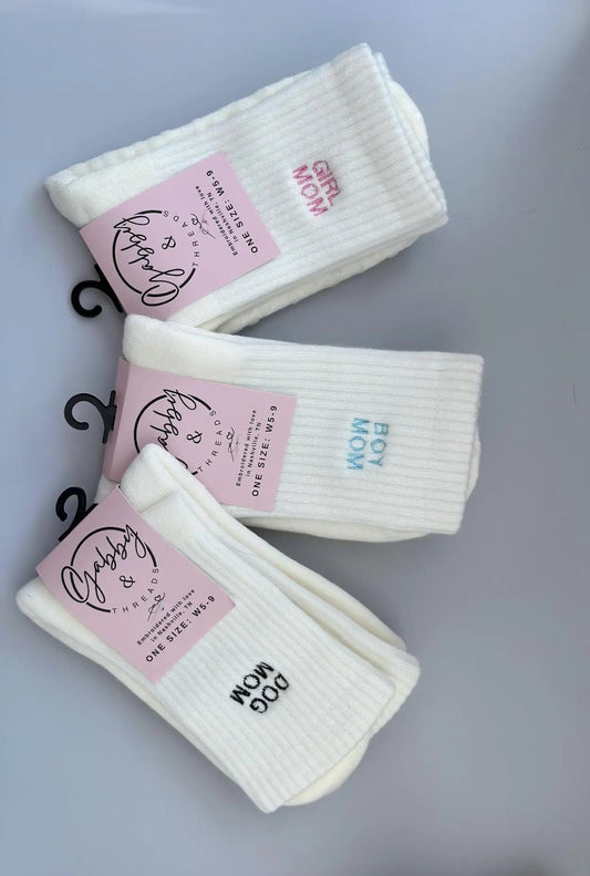 three pairs of crew socks with the words "dog mom" "boy mom" or "girl mom" embroidered on them