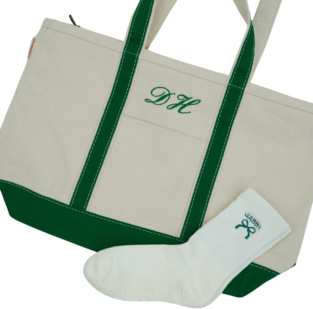 Beige tote bag with green trim and monogram, accompanied by a white sock with a green logo.