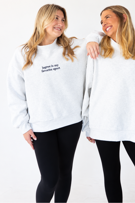 two models are standing next to each other. the model on the left is wearing an embroidered mock neck sweatshirt that says "lagree is my favorite sport"