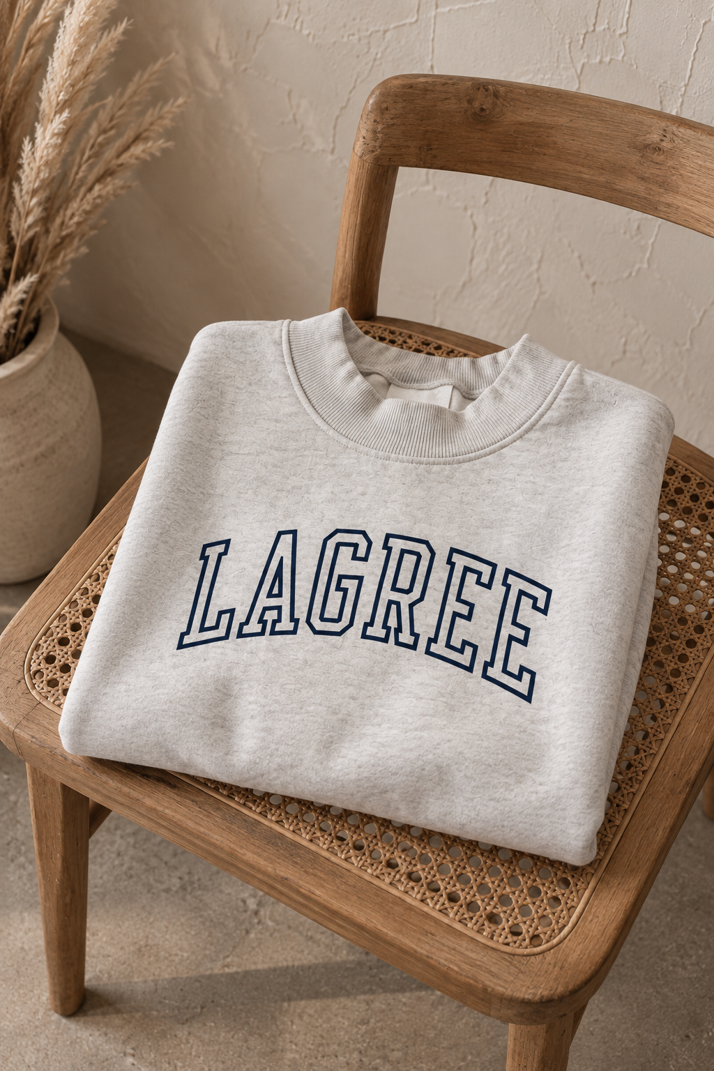 a heather gray mock neck with the word "lagree" embroidered on it is folded on a chair