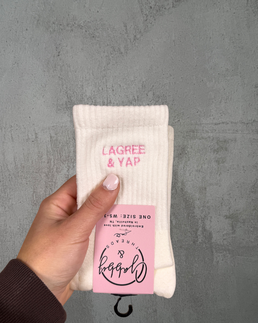 a pair of white grip socks with the text "Lagree & Yap" embroidered on them