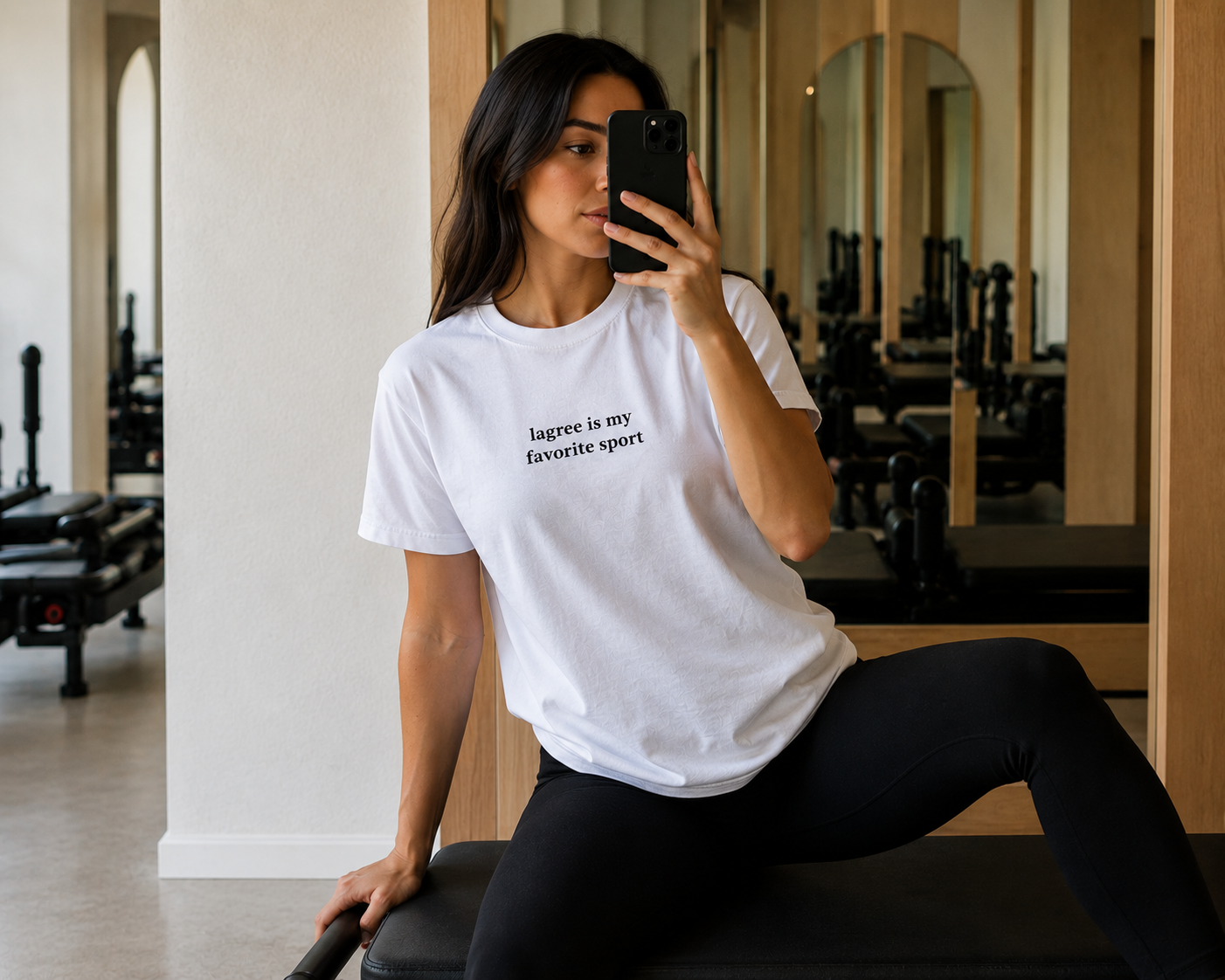 a women is in a lagree studio wearing a shirt that says "lagree is my favorite sport"