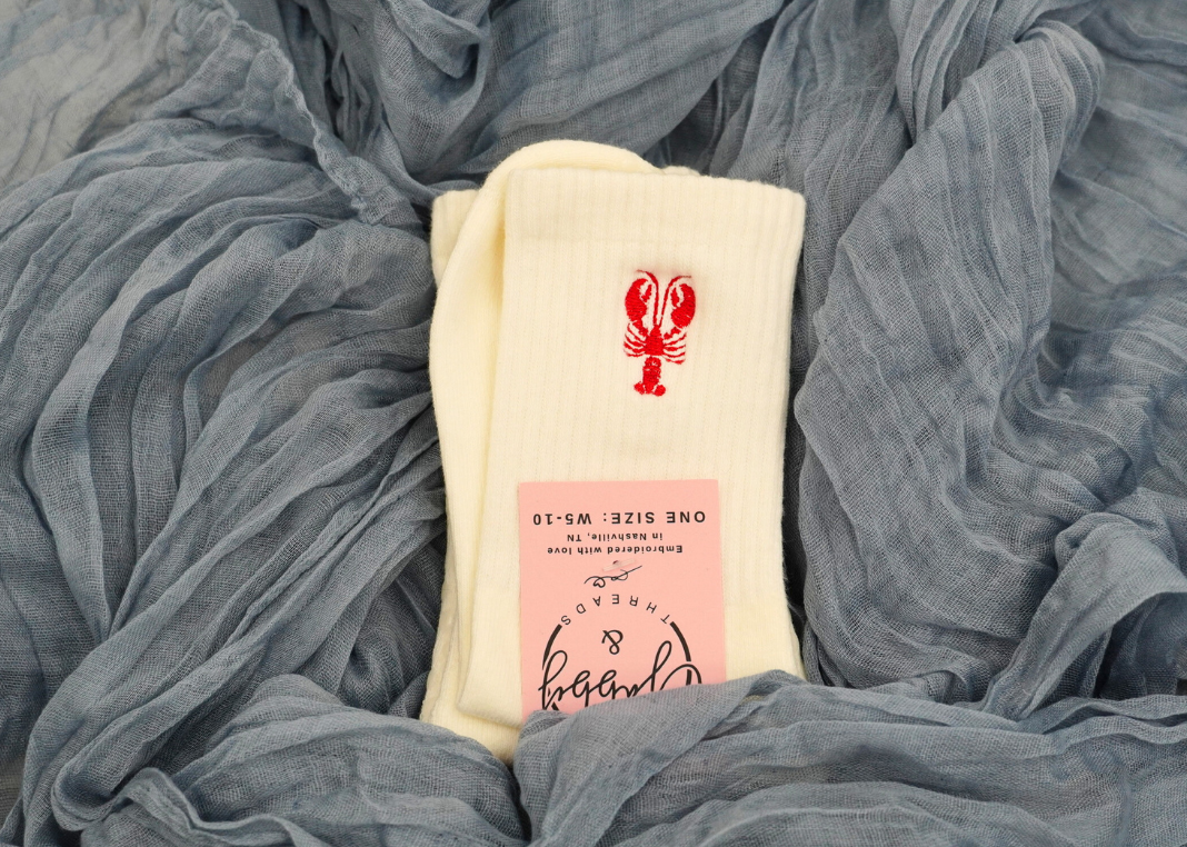 a pair of white grip socks with an embroidered lobster on them
