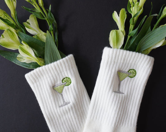 White socks with green margarita embroidery on a black background with green flowers