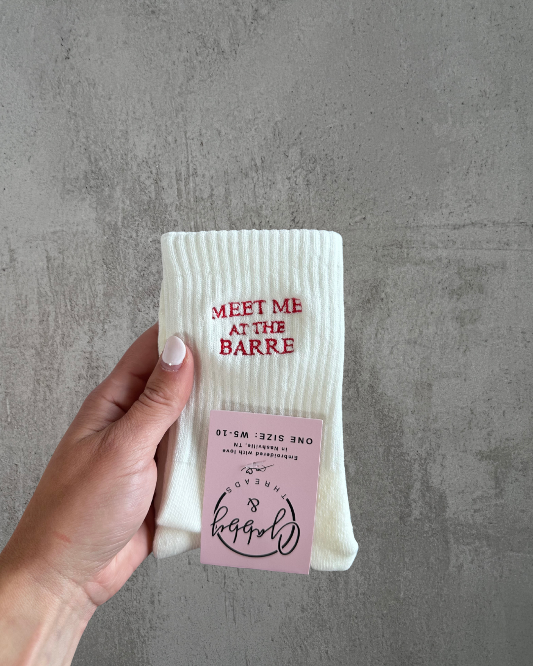 a pair of white grip socks with the words "meet me at the barre" embroidered on them