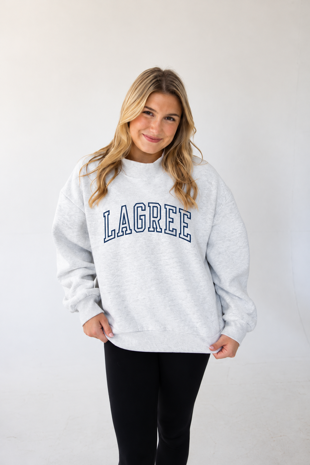 a model is wearing a heather gray mockneck sweatshirt with the word "LAGREE" embroidered on it
