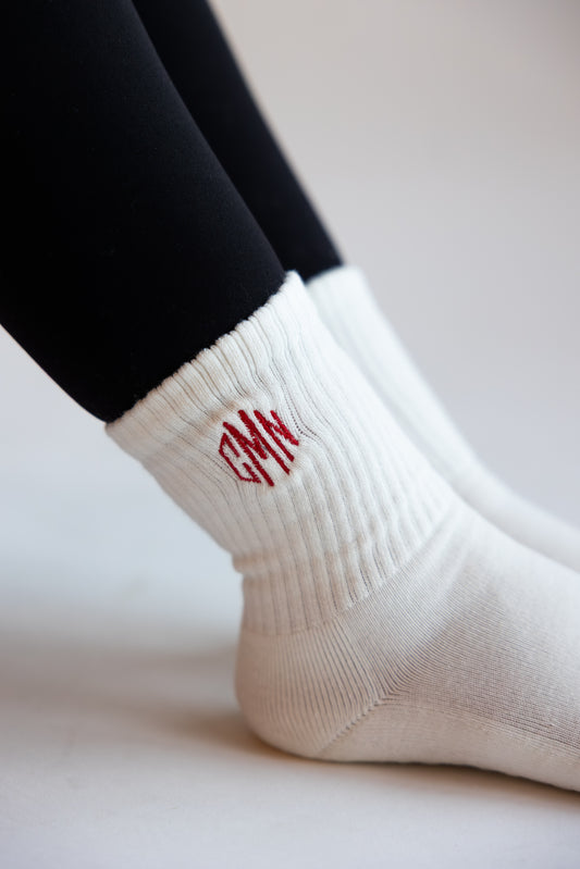 a pair of white grip socks with an embroidered monogram on them