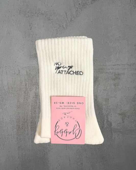 a pair of white grip socks with the words "no springs attached" embroidered on them