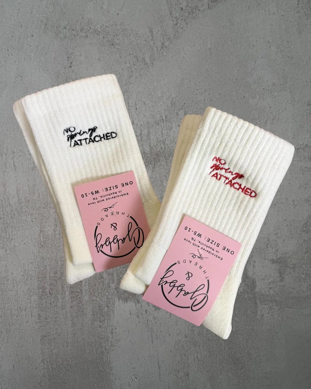two pairs of white grip socks with the words "no springs attached" embroidered on them